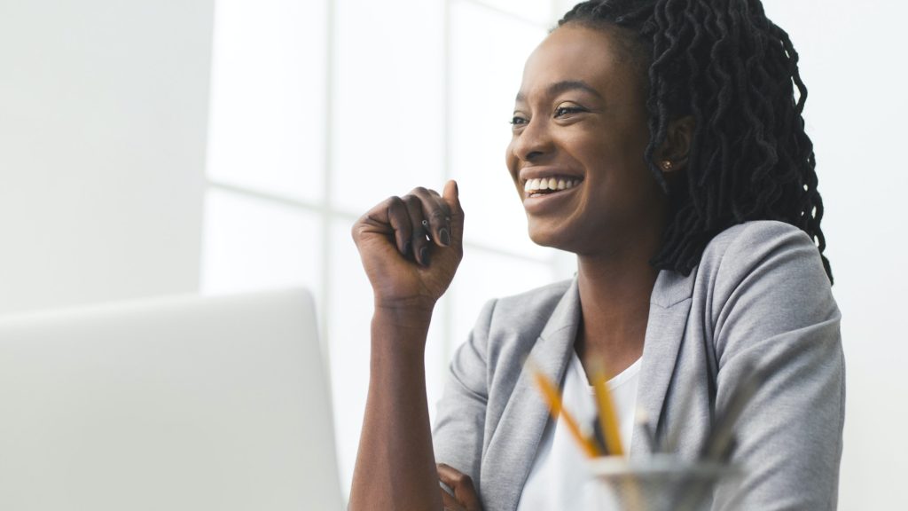 Portrait Of Afro Business Lady Laughing Sitting Against Window